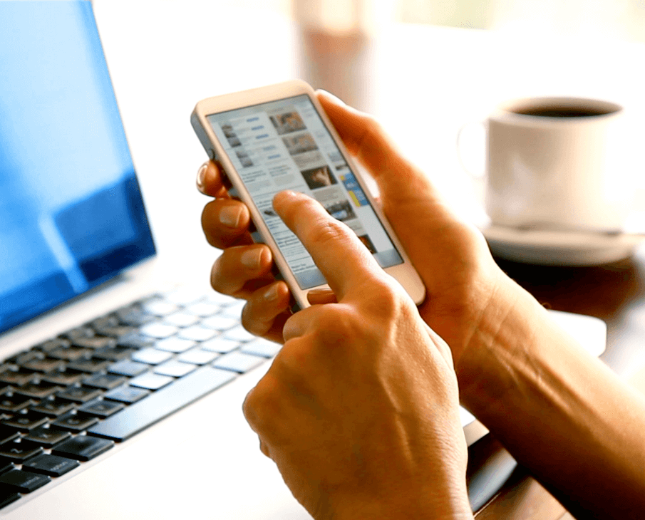 Person at computer looking at mobile phone