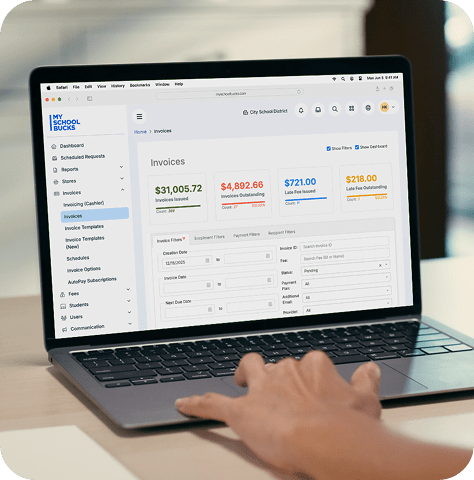 A hand scrolls on a laptop while showing the software for MySchoolBucks invoicing capabilities.