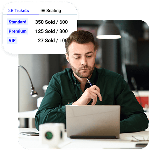 A person working at their desk is framed next to a small graphic that shows a seating chart capacity for an event they’re creating.