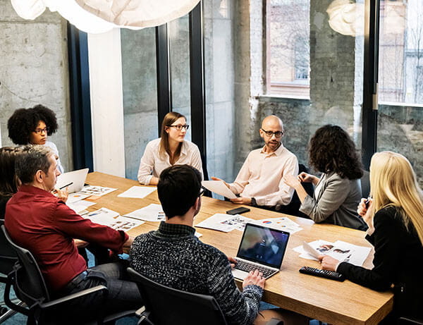Photo of a diverse group of people sitting around an office meeting room
