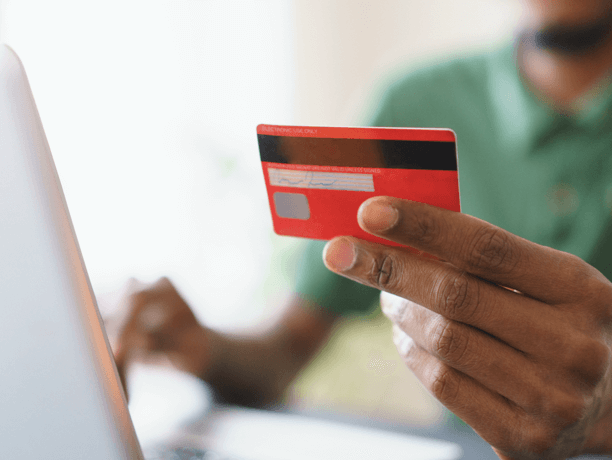 Close up of woman's hand holding credit card while looking at laptop