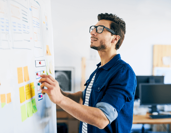 Man with classes standing up and looking at diagram on easel